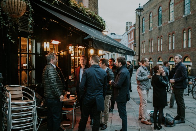 A group of friends having a drink together at an english pub terrace, in London city, England.