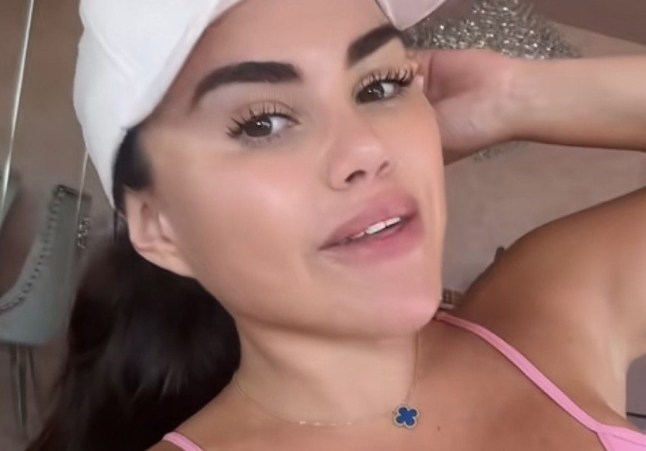 Katija Cortez poses for a selfie, wearing a pink tank top and a hat.